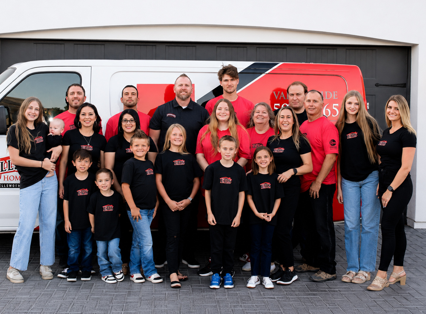 Large group of people posing in front of a van in matching black and red shirts, smiling, with a branded vehicle.