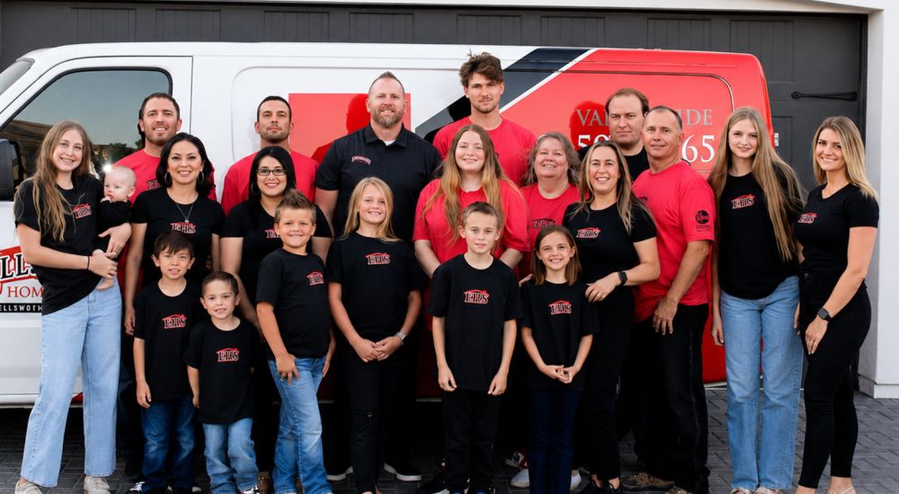 Large group of people posing in front of a van in matching black and red shirts, smiling, with a branded vehicle.