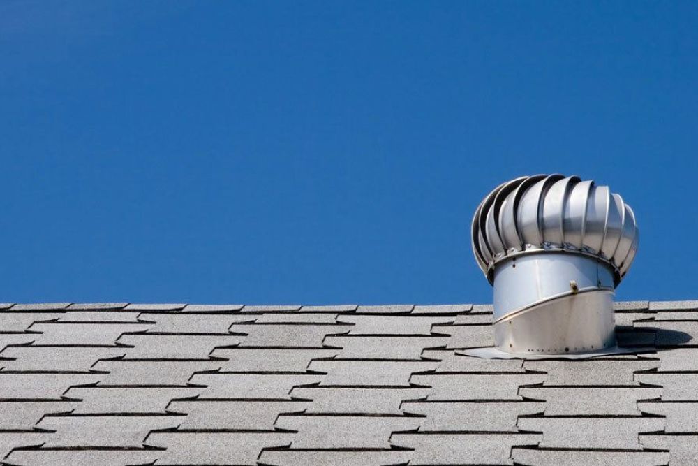 Modern gray roof with a spinning vent turbine under a clear blue sky, showcasing efficient attic ventilation.