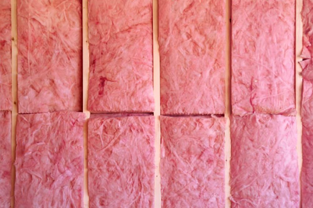 Pink fiberglass insulation panels lined up on a wall, ready for installation in a home construction project.
