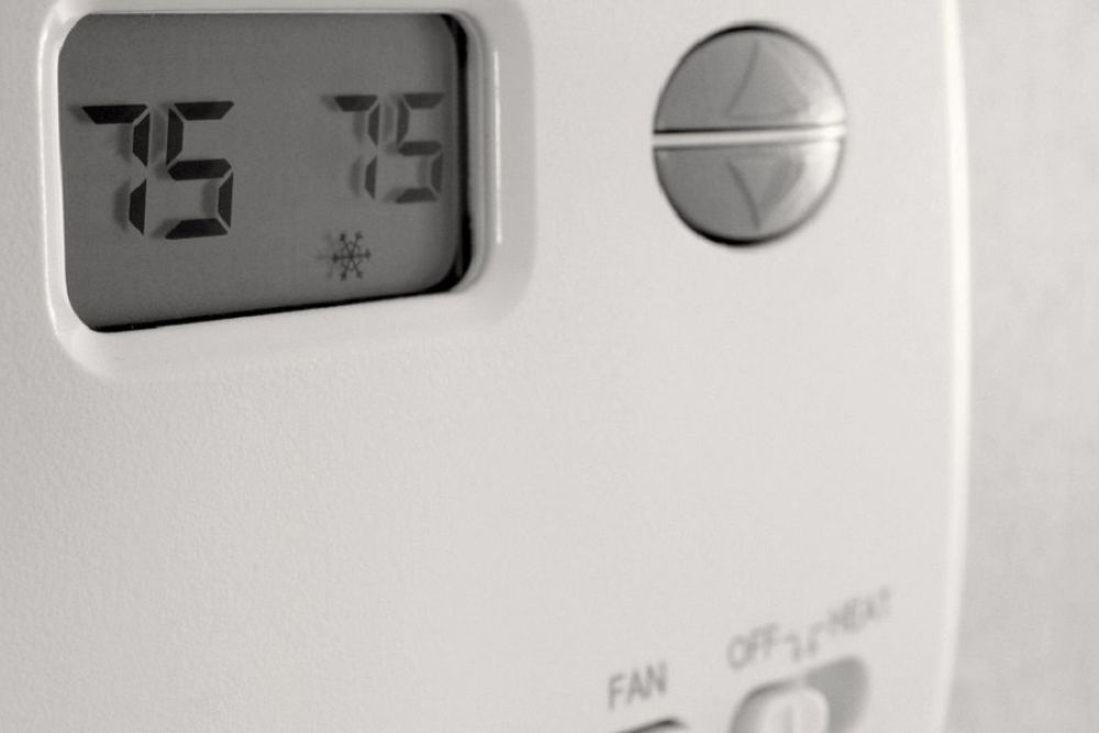 Digital thermostat displaying 75 degrees Fahrenheit, featuring cooling mode symbol, close-up view.