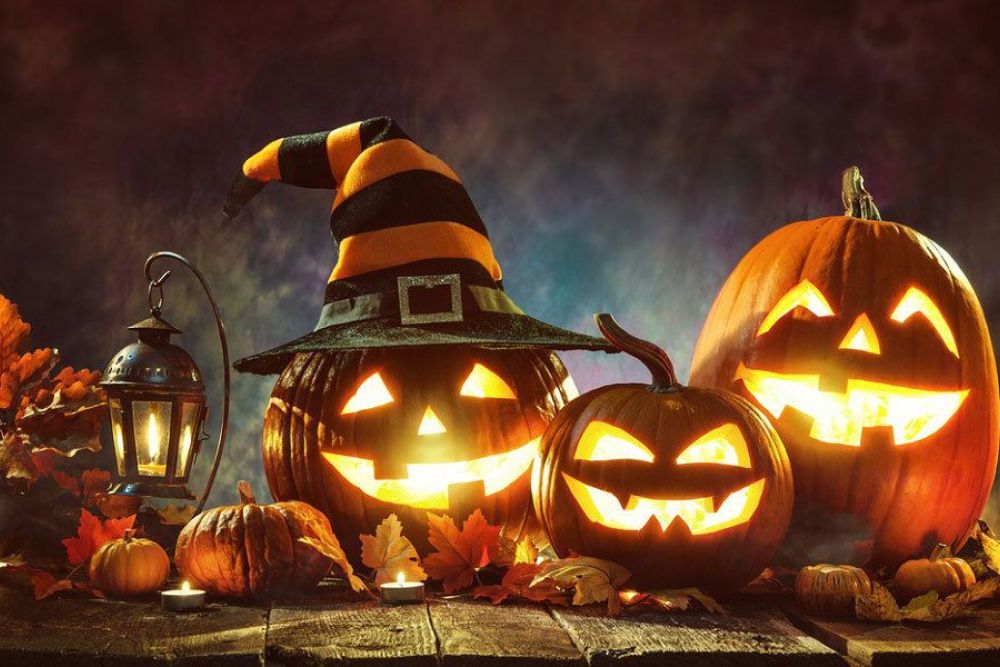 Halloween scene with glowing jack-o'-lanterns, witch hat, autumn leaves, and lantern for a spooky festive vibe.