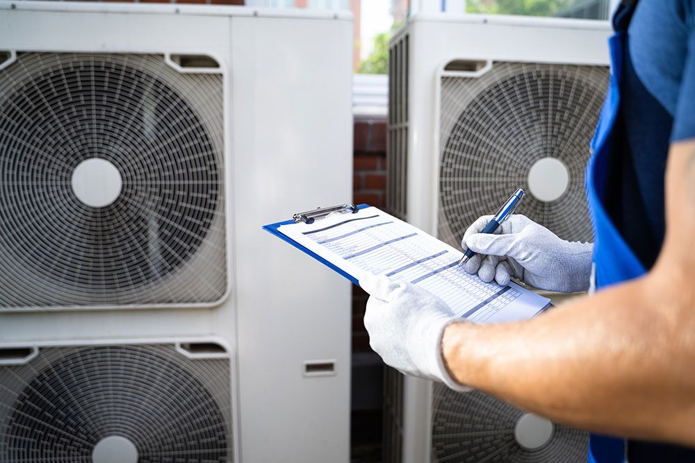 Technician inspecting air conditioning units with a checklist outside a building.