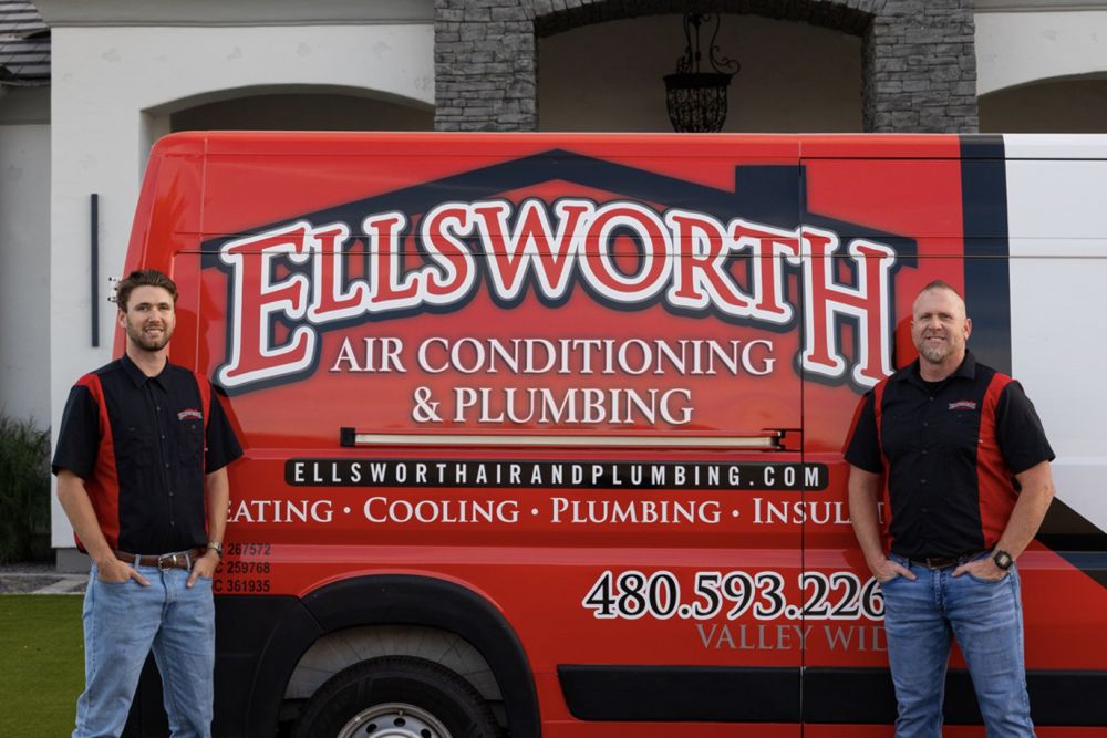 Two workers standing by a red Ellsworth Air Conditioning and Plumbing van, showcasing company services.
