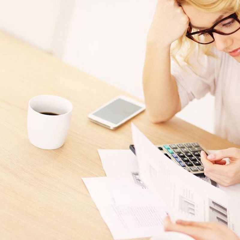 Couple reviewing financial documents with calculator and coffee, focused on budgeting and planning at wooden table.