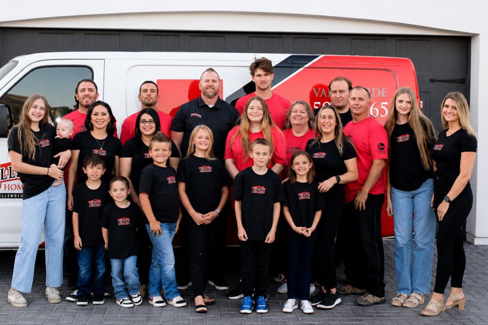 Large group of people posing in front of a van in matching black and red shirts, smiling, with a branded vehicle.