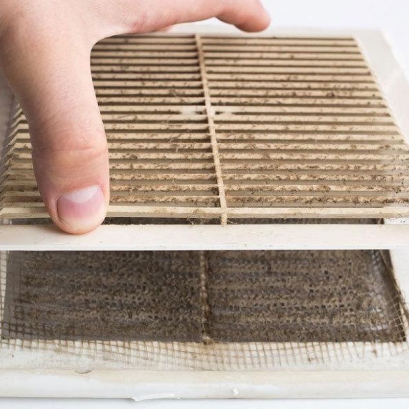 Hand removing dirty air vent cover for cleaning maintenance.