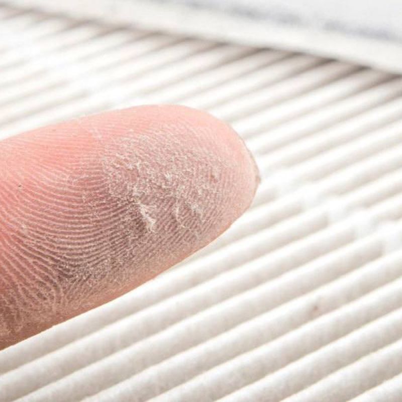 Close-up of a finger with dust showing HVAC air filter needing cleaning or replacement for better air quality.