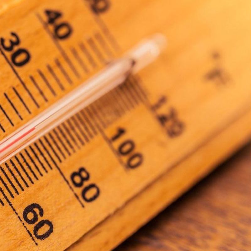 Close-up of a thermometer showing temperature in Fahrenheit and Celsius, highlighting warm climate conditions.