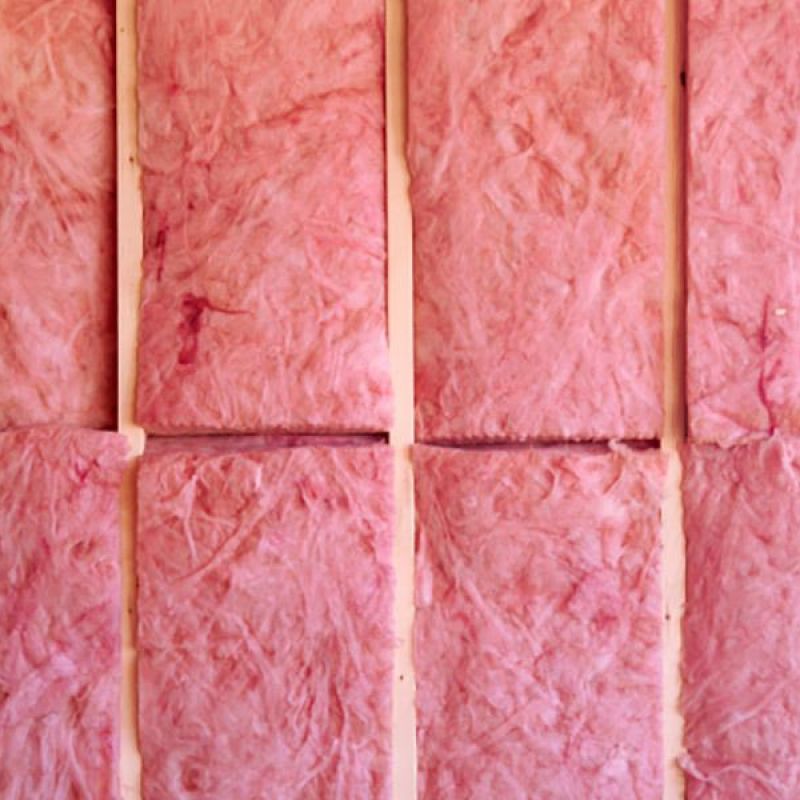 Pink fiberglass insulation panels lined up on a wall, ready for installation in a home construction project.