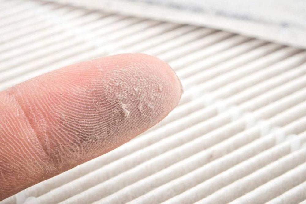 Close-up of a finger with dust showing HVAC air filter needing cleaning or replacement for better air quality.